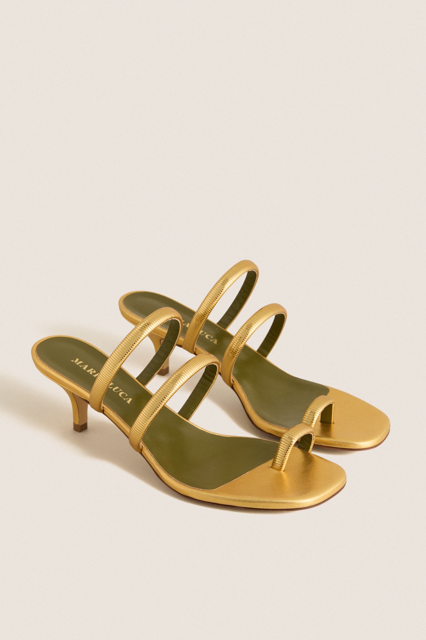 Gold Modia Sandals: Classic, metallic gold low-heeled sandals with elegant straps and toe-loop, offering effortless glamour and fun for high-end, versatile styling.