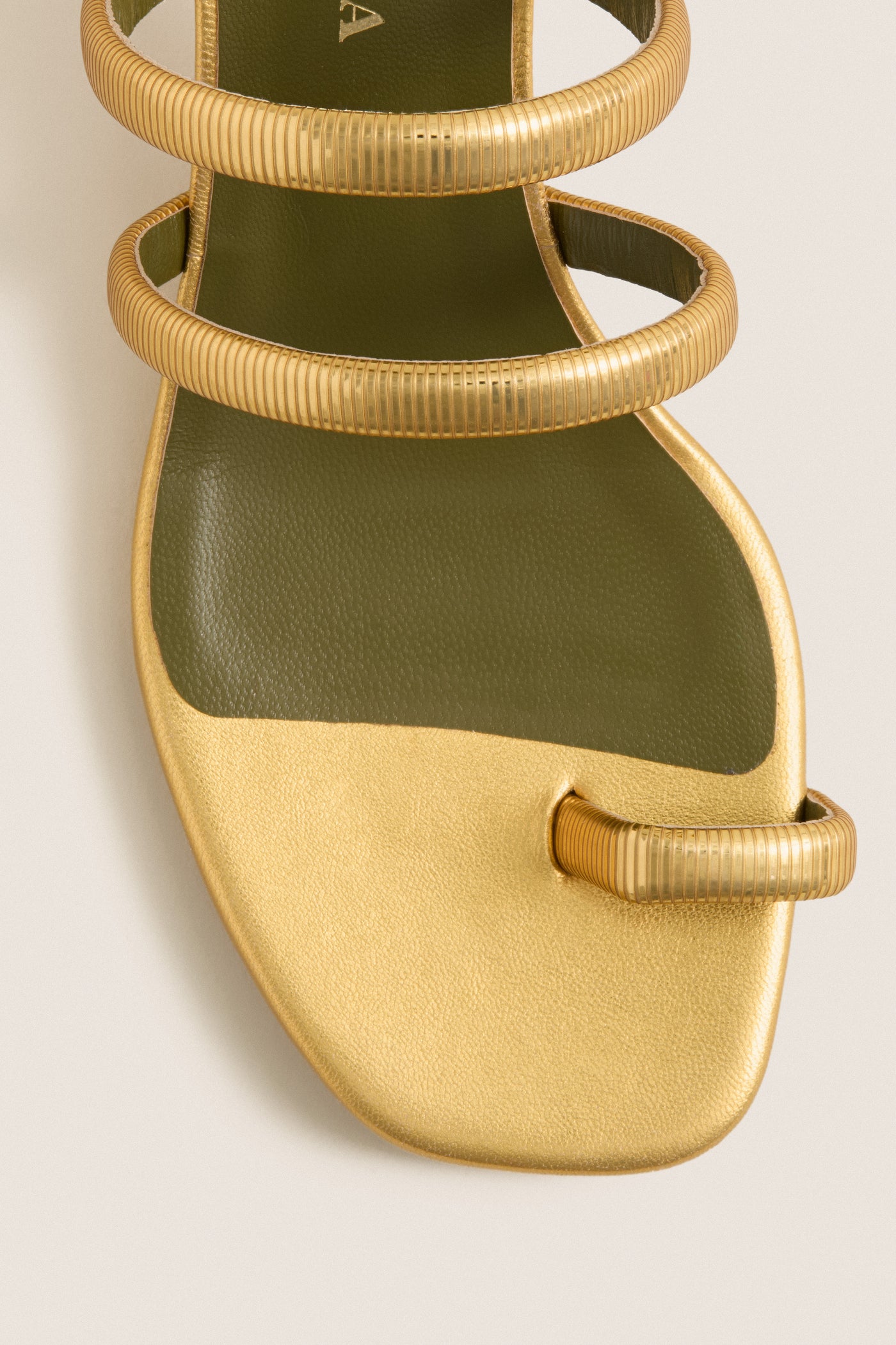 Gold Modia Sandals: Classic flat sandal with metallic gold textured straps, olive-green footbed, and toe-loop. Effortlessly high-end, perfect for fun, polished looks.