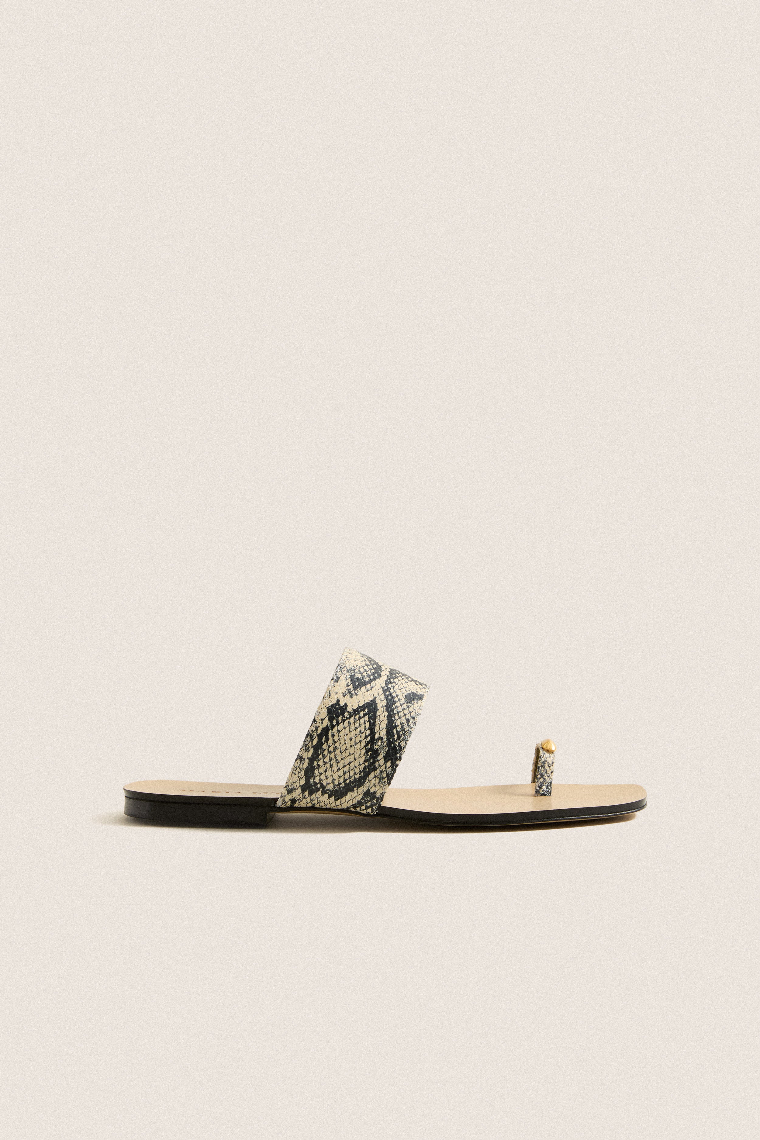 Natural Snake Oleandra Capri Flat Sandals, featuring a classic slip-on design with a snakeskin-print leather strap and gold studded toe loop, embody effortless, high-end style.