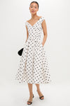 Model in a classic Cream Polka Dot Cotton Midi Dress with an effortless wrap-style bodice, fun polka dots, and a high-end full skirt, styled with black sandals.