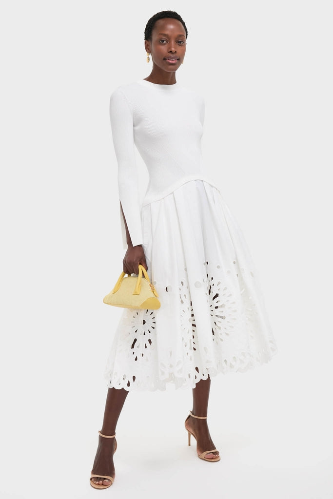 Model showcases an effortless, high-end look with a classic white ensemble, complemented by a Butter EW Dome Clutch and metallic-gold sandals for a fun, confident style.