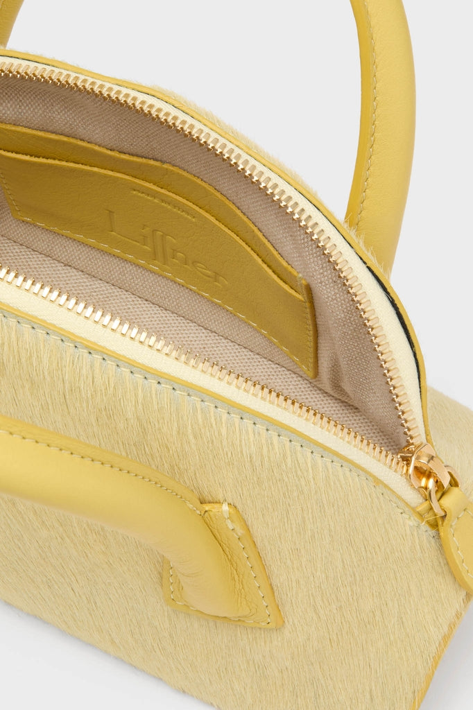 Butter EW Dome Clutch, a classic, high-end handbag with a hair-calf exterior, smooth leather handles, and gold-tone zipper, embodies effortless elegance and fun sophistication.