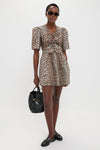 Model in a leopard-print dress, accessorized with small gold hoop earrings and sunglasses, showcasing a classic Black Glossy Belted Bucket Bag, exuding an effortless, high-end style.