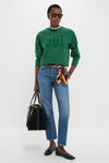 Woman in a forest-green sweatshirt, jeans, and flats, holding a classic Black Suede Large Sprout Tote, exuding an effortless, high-end style with fun silk scarf accent.