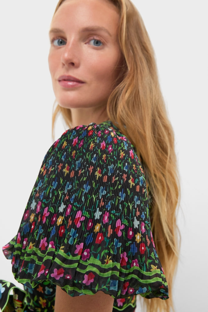 Model in Black Celestia Dress with vibrant floral print, puff sleeves, and green striped hem, embodying classic elegance and effortless, high-end style.
