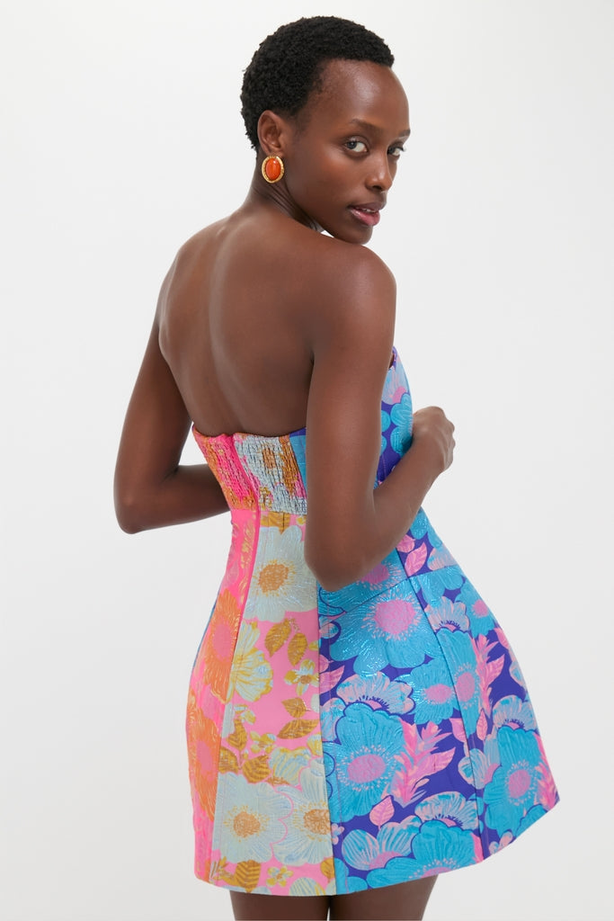 Woman in a classic, strapless Multi Cosmica Dress with bold floral patchwork and metallic jacquard, showcasing an effortless, fun, high-end look.