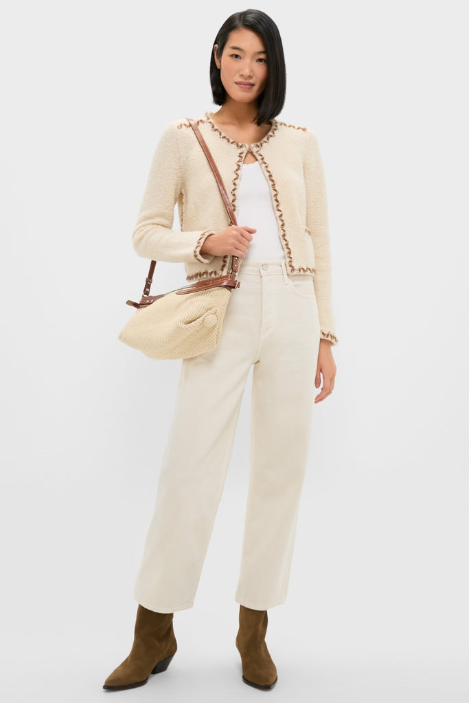 Model wearing the Ecru and Bronze Rochelle Cardigan, a classic, high-end wool piece with brown whipstitch trim. Effortlessly styled with off-white jeans and suede boots.