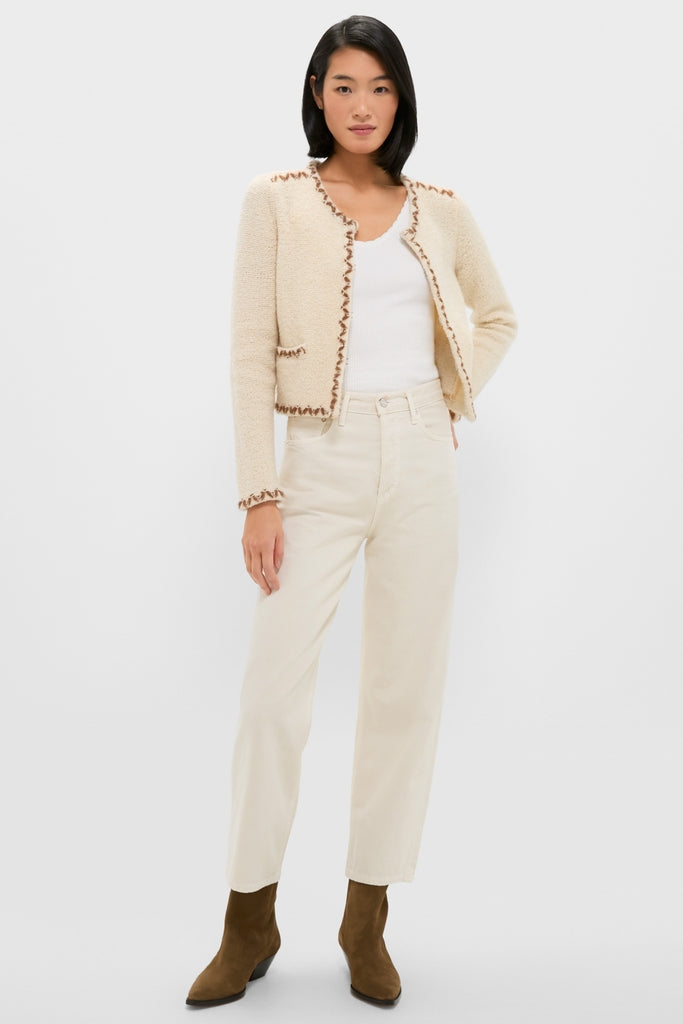 Woman models the classic Ecru and Bronze Rochelle Cardigan with contrasting trim, paired effortlessly with off-white jeans and olive-brown suede boots for a chic, high-end look.