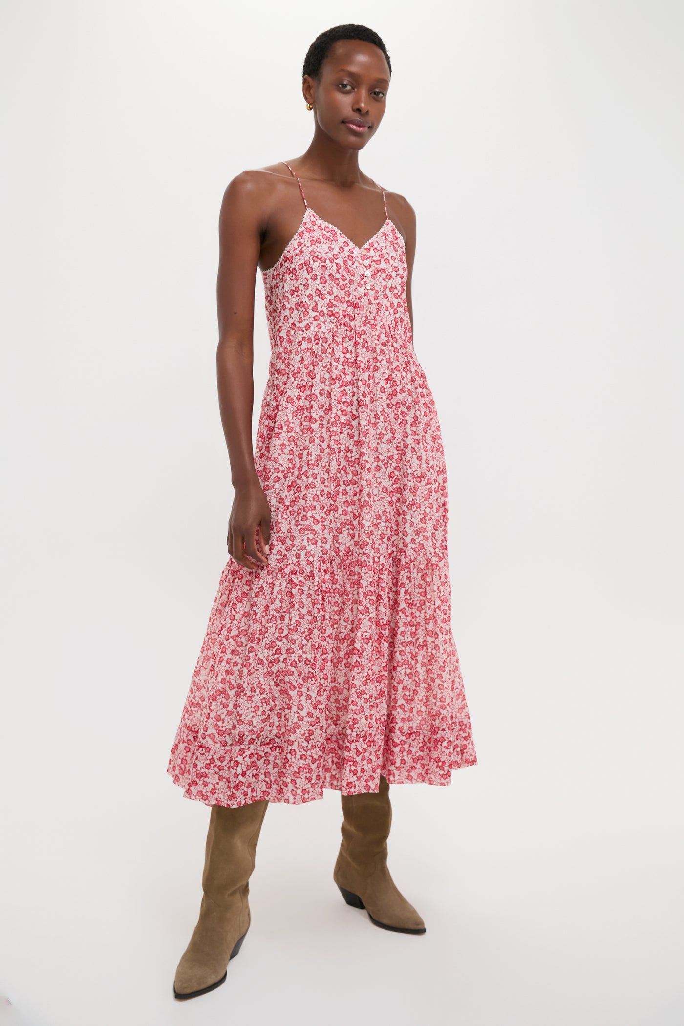 Woman in the Red Sabba Dress, featuring classic tiered design and effortless style, paired with tan suede boots, embodying a fun, high-end, warm-weather look.