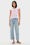 Young woman in a classic, effortless Light Pink Nalou Top with ruffle accents and flutter sleeves, paired with high-waisted jeans, embodying a fun, high-end style.