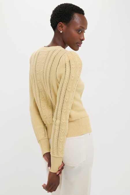 Woman models classic Light Yellow Kalyn Sweater with open-stitch detail, pleated shoulders, and ribbed hem, paired effortlessly with high-waisted pants for a high-end, fun look.