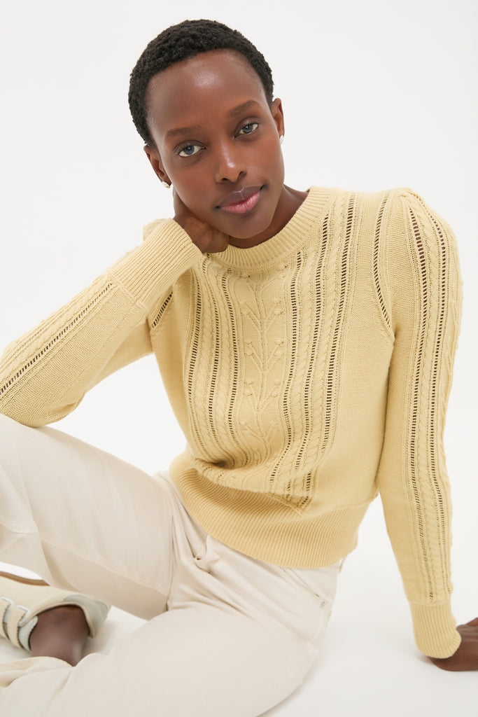 Young person in an effortlessly classic Kalyn Sweater, showcasing delicate cable knit and pleated shoulders, embodying Tuckernuck's high-end, fun, and chic style.