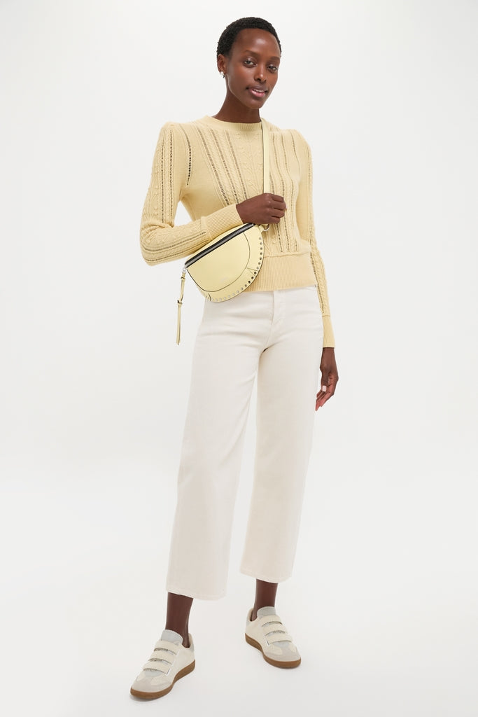 Woman modeling the classic Light Yellow Kalyn Sweater with cable knit details, paired effortlessly with high-waisted trousers and sneakers, embodying a fun, high-end aesthetic.