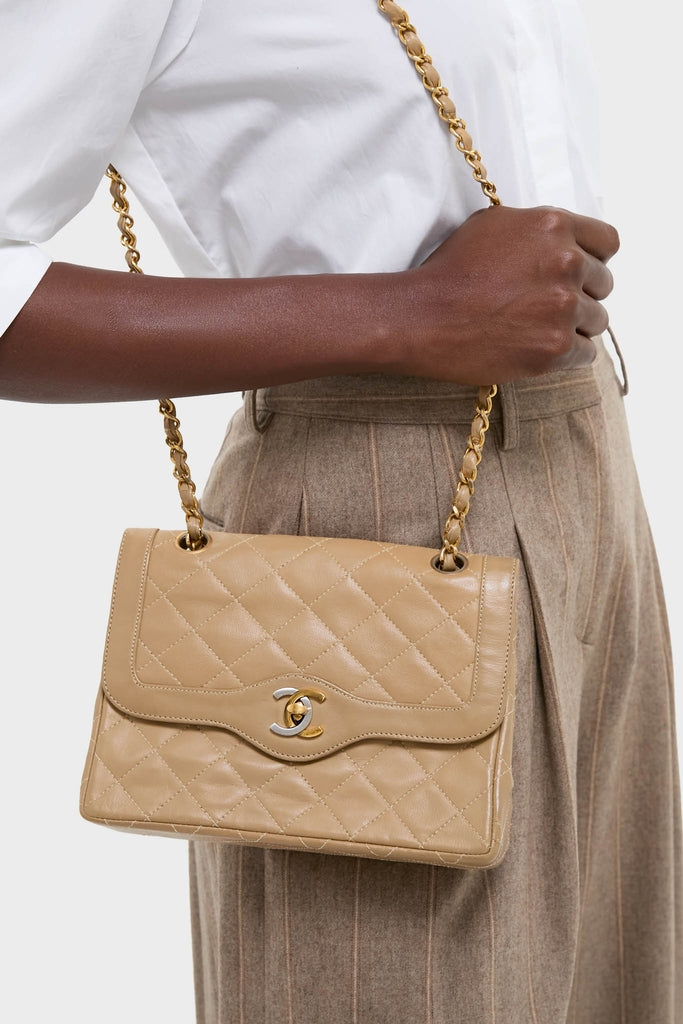 CHANEL CC Mini Paris Double Flap Bag in tan quilted leather, featuring a classic gold-tone chain strap and interlocking CC clasp, exudes effortless, high-end sophistication.