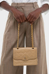 CHANEL CC Mini Paris Double Flap Bag, a classic quilted leather shoulder bag with gold chain and logo clasp, held effortlessly by someone in stylish pinstriped trousers.