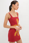 Person in profile wearing the Cattleya Carmin Siela Dress, a sleeveless red mini dress with a square neckline and bold floral graphic, embodying classic, effortless, high-end style.