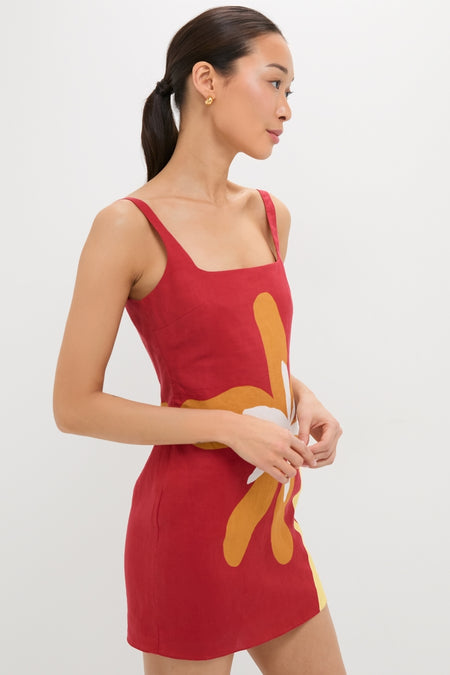 Person in profile wearing the Cattleya Carmin Siela Dress, a sleeveless red mini dress with a square neckline and bold floral graphic, embodying classic, effortless, high-end style.