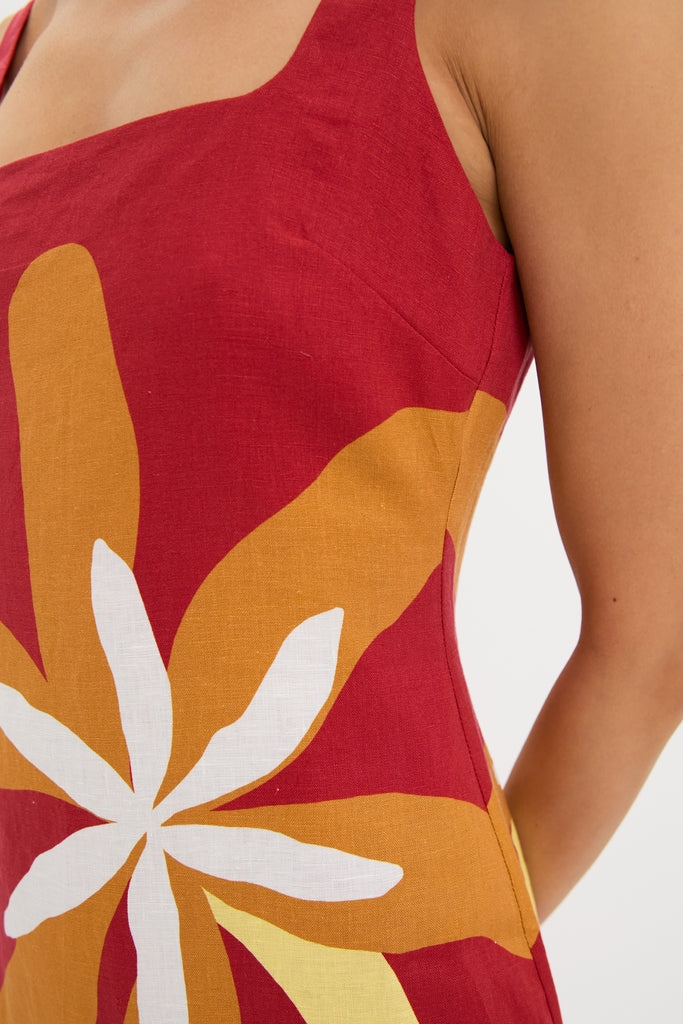 Woman wearing the Cattleya Carmin Siela Dress, featuring a classic square neckline and vibrant floral pattern, embodying effortless, high-end style with a fun, chic silhouette.