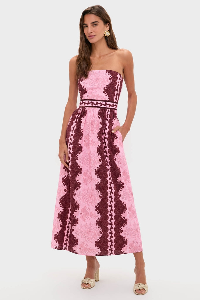Model in Blush and Maroon Abstract Bennet Midi Dress with burgundy lace patterns, side pockets, and gold-tone bow-accented mules, embodying a classic, effortless, high-end style.