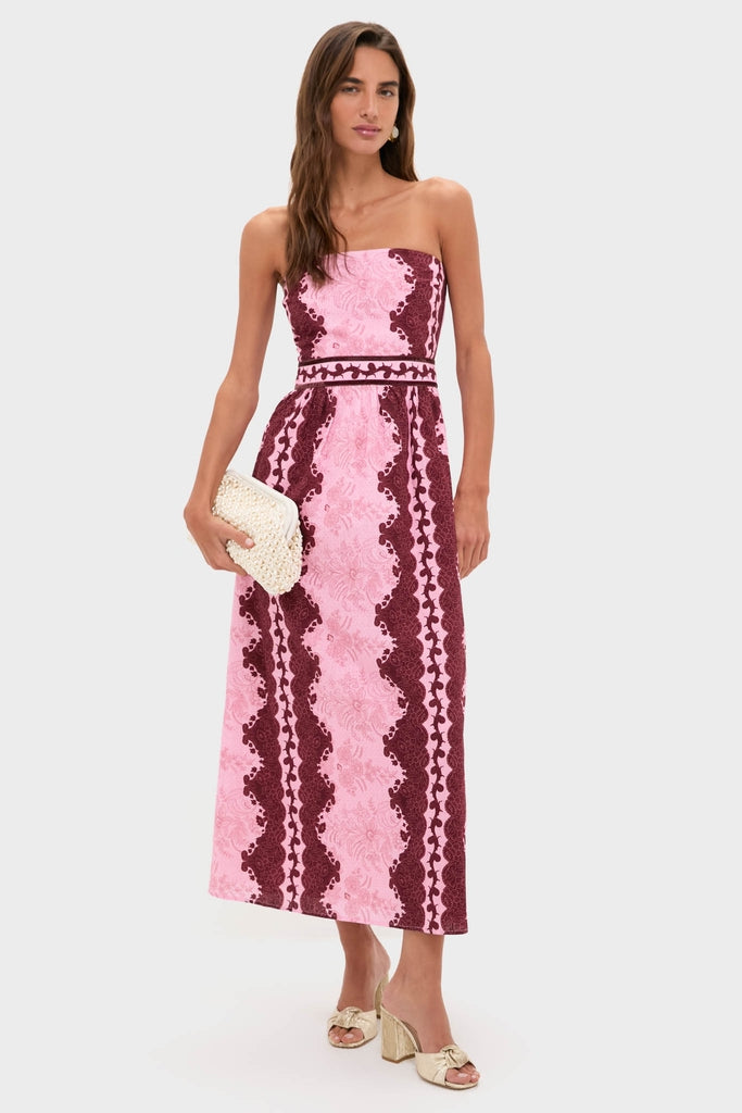 Model in the Blush and Maroon Abstract Bennet Midi Dress, featuring a classic, effortless design with lace-style motifs, paired with a fun woven clutch and high-end metallic sandals.