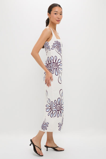 Namur Celeste Amaranta Dress: A classic, sleeveless white dress with abstract purple spirals, offering an effortless, high-end look, paired with fun black heeled thong sandals.