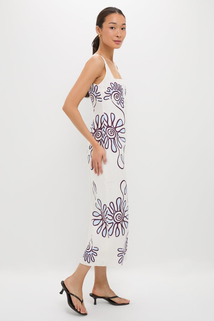 Namur Celeste Amaranta Dress: A classic, sleeveless white dress with abstract purple spirals, offering an effortless, high-end look, paired with fun black heeled thong sandals.