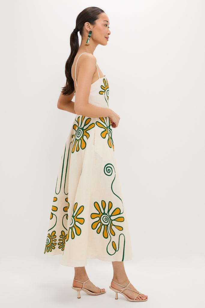 Model wearing the Namur Ivory Delta Dress, a classic and effortless sundress featuring stylized floral prints and spaghetti straps, paired with nude heels and tassel earrings.