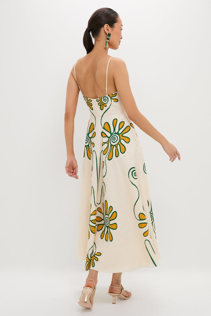 Woman in a Namur Ivory Delta Dress, featuring classic, fun daisy-like flowers and swirling stems, paired with nude heeled sandals for an effortless, high-end look.