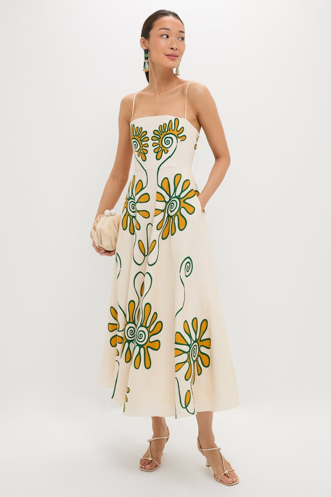 Model wearing the Namur Ivory Delta Dress, a classic, high-end midi sundress with an effortless A-line silhouette, bold floral print, and holding a fun ruched clutch.