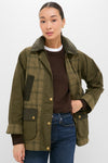 Model wearing Dusky Green Modern Tartan Beadnell Casual Jacket with corduroy collar, over dark sweater and jeans; a classic, effortless, and fun high-end countryside style.