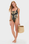 Woman wearing the Namur Black and White Vienna One Piece swimsuit with bold floral motifs, holding a straw tote, exuding a classic, effortless, and high-end style.