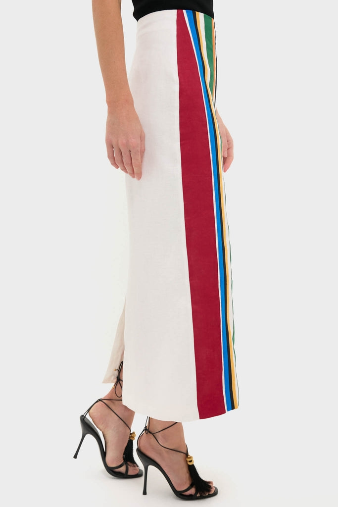 Woman wearing the Roman Lima Midi Skirt, a classic cream ankle-length piece with a bold, colorful stripe and back slit, styled with effortless high-end black lace-up stiletto sandals.