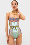 Model in a classic Pastel Patchwork Lucent One Piece swimsuit with paisley print, exuding effortless style. Features include a fabric belt, chunky necklace, and hoop earrings.