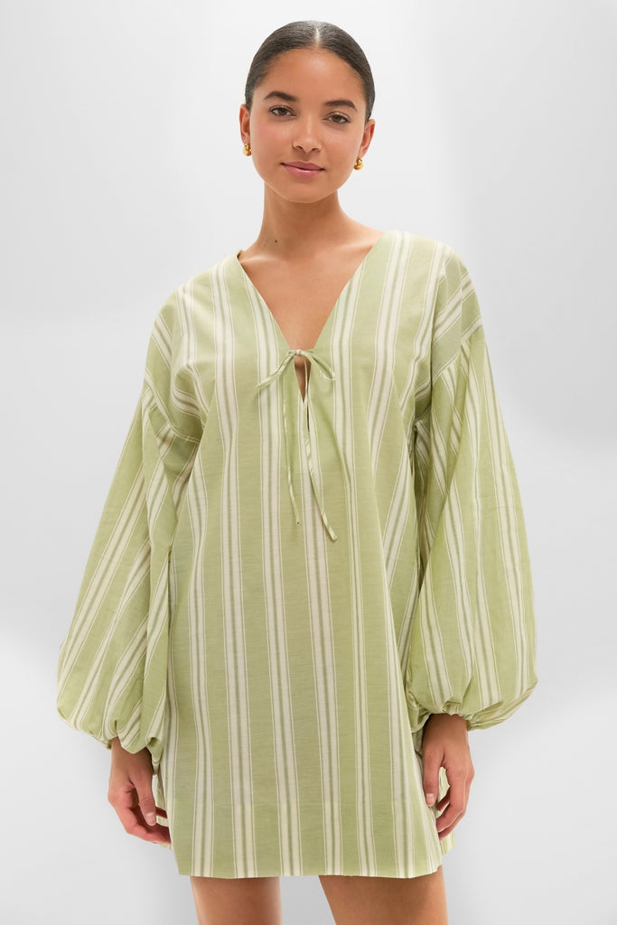 Woman models the Faded Juniper Ombre Stripe Pia Mini Dress with classic pinstripes, effortless V-neck tie, and fun, high-end balloon sleeves, embodying a relaxed, chic silhouette.
