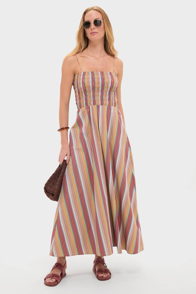 Woman models the classic Mustard Agua Stripe Annikekn Maxi Dress, featuring an effortless A-line silhouette with adjustable straps. She accessorizes with sunglasses, a woven handbag, and sandals.