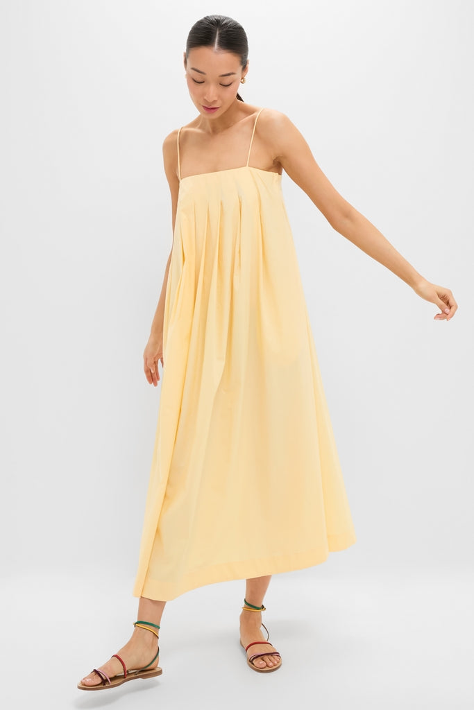 Woman in a classic, effortless Banana Lopez Midi Dress with a relaxed A-line silhouette, adjustable straps, and box pleats, styled with fun, high-end strappy sandals.