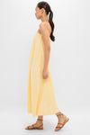 Young woman in profile wearing the classic Banana Lopez Midi Dress, featuring an effortless A-line silhouette and thin straps, styled with colorful sandals and gold hoops.