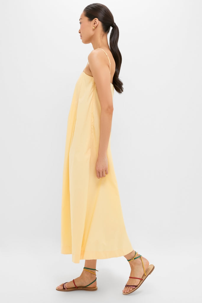 Young woman in profile wearing the classic Banana Lopez Midi Dress, featuring an effortless A-line silhouette and thin straps, styled with colorful sandals and gold hoops.