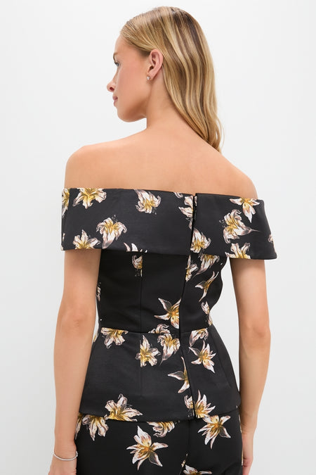 Woman wearing the Black and Yellow Souline Top, an off-the-shoulder piece with light lily pattern, embodying a classic and effortless high-end style, paired with matching bottoms.