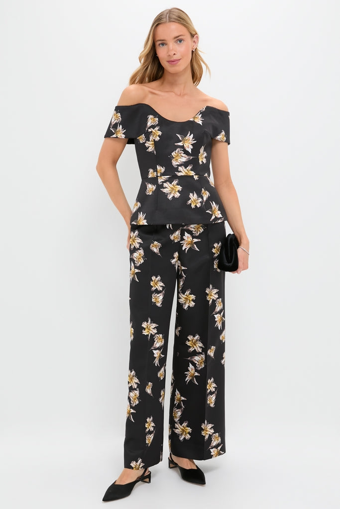 Model in the Black and Yellow Souline Top, an off-shoulder peplum blouse with matching high-waisted, wide-leg pants, carrying a black clutch and wearing slingback heels.