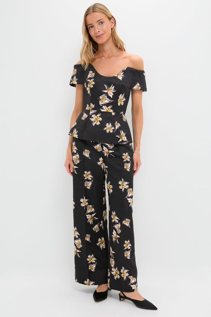Woman models the Black and Yellow Souline Top, a classic, high-end off-the-shoulder peplum with effortless floral print, paired with matching trousers for a fun, coordinated look.