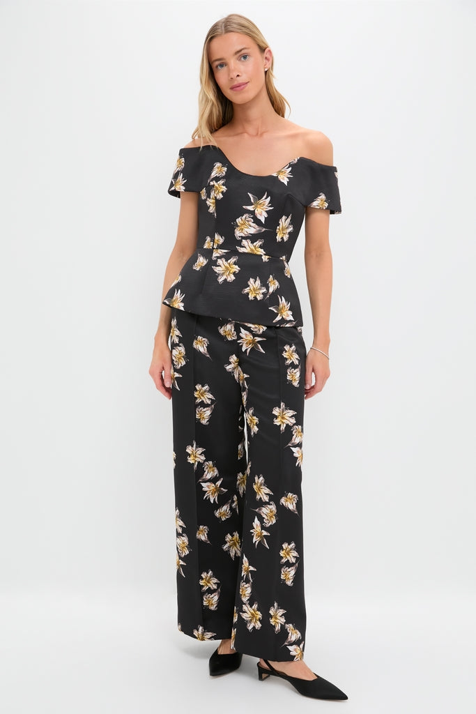 Woman models classic Black and Yellow Daffy Trousers with matching off-the-shoulder peplum top, featuring a fun yellow-and-white floral print, creating an effortless, high-end look.