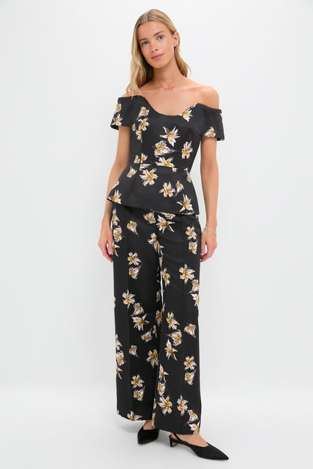 Woman models classic Black and Yellow Daffy Trousers with matching off-the-shoulder peplum top, featuring a fun yellow-and-white floral print, creating an effortless, high-end look.