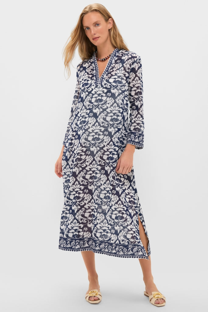 Woman modeling the Dark Blue Giada Caftan, a classic, ankle-length dress with a V-neckline, white damask print, and fun side slits; effortlessly paired with a beaded necklace.