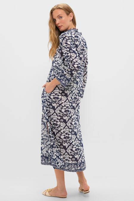 Model in a classic, effortless Dark Blue Giada Caftan with a white navy damask print, featuring a front slit, rolled sleeves, and side pockets, paired with neutral slide sandals.