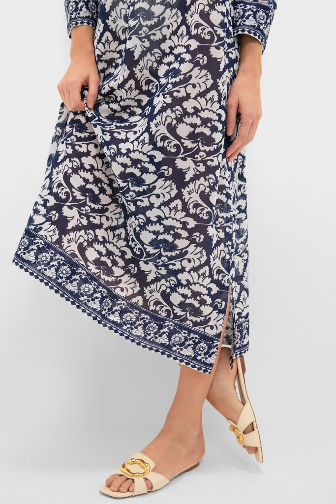 Person wearing classic Dark Blue Giada Caftan with floral print, showcasing an effortless, fun style. The midi dress reveals high-end beige slide sandals with gold buckle detail.