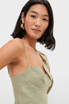 Young woman in a Green Striped Monsterea Leaf Sleeveless Midi Dress with gold hoop earrings, embodying a classic, effortless style. The dress's design is fun and high-end.