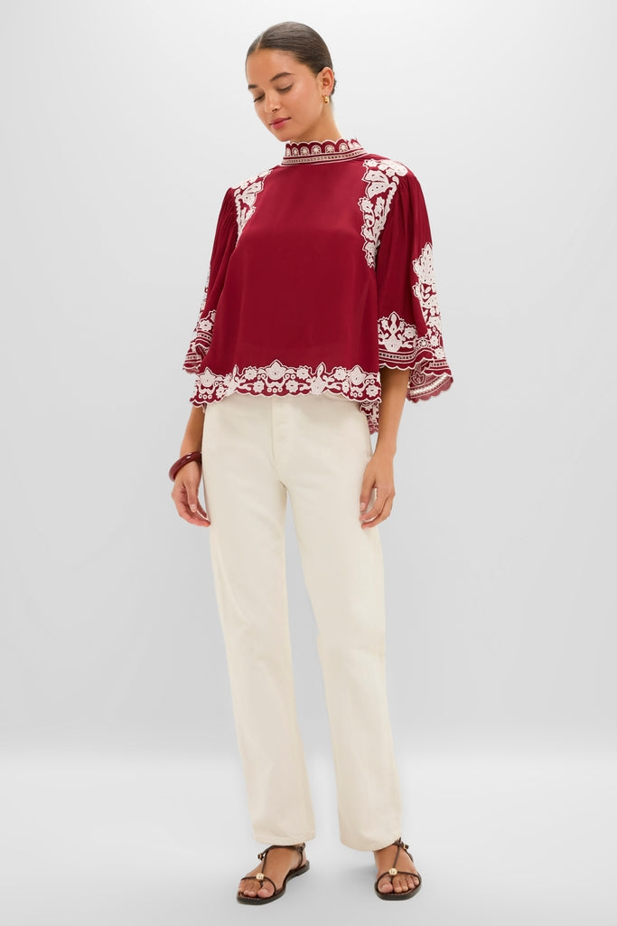 Model wearing Burgundy Bicolor Palm Tree Embroidery Blouse with floral trim, paired with off-white trousers. Classic, effortless style, embodying Tuckernuck's fun, high-end fashion ethos.