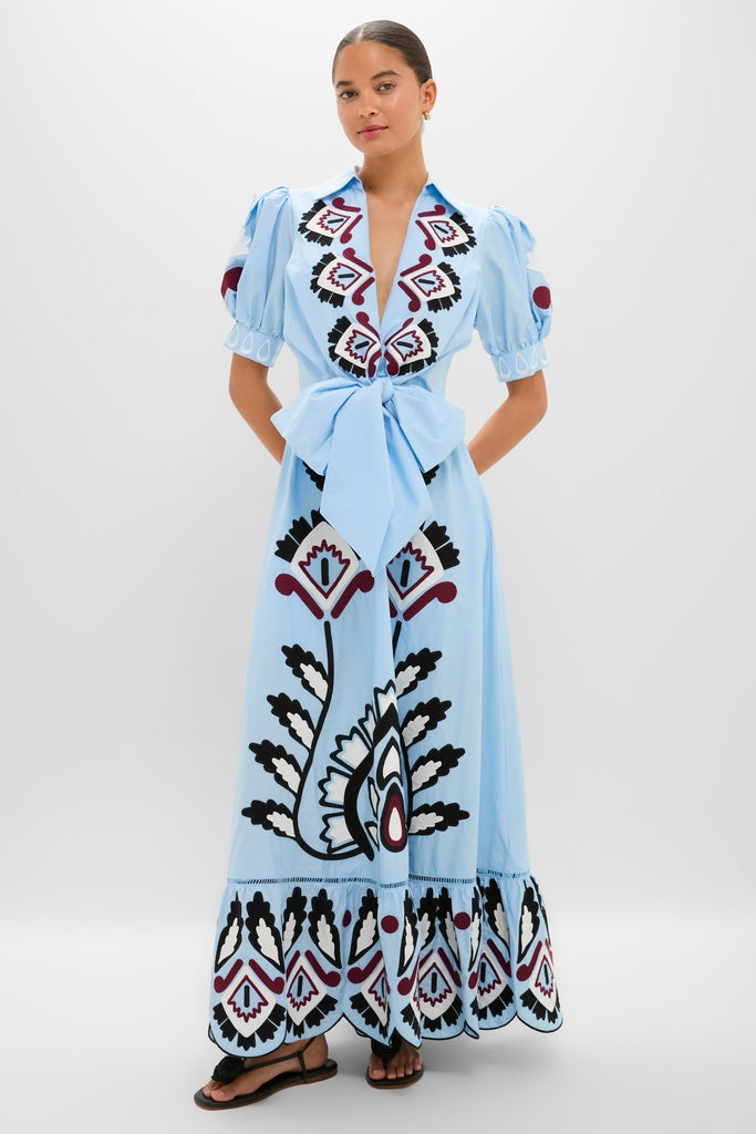 Woman in Blue Artisanal Short Sleeve Maxi Dress with a deep V-neck, floral embroidery, puffed sleeves, and a flared skirt, exuding a classic, effortless, high-end style.
