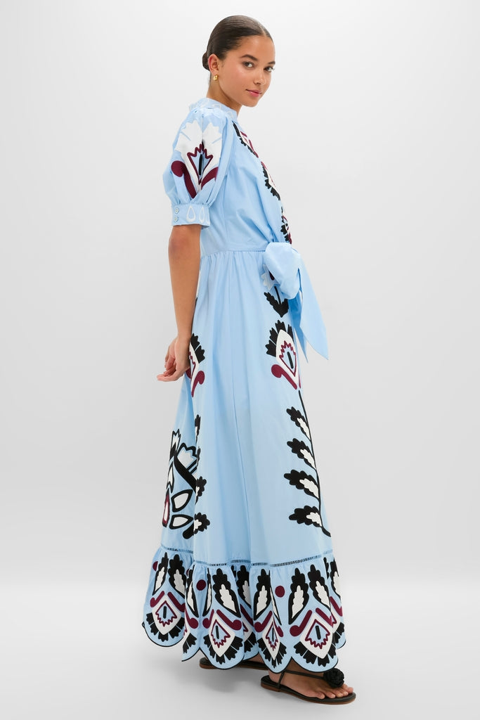 Young woman models the Blue Artisanal Short Sleeve Maxi Dress, showcasing its classic, effortless design with embroidered motifs and scalloped hem, paired with fun, high-end black sandals.